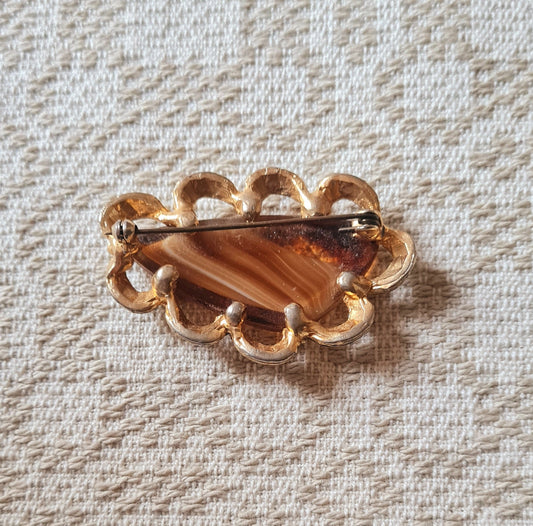 Spilla con pietra color ambra, montatura dorata e dettagli ornamentali