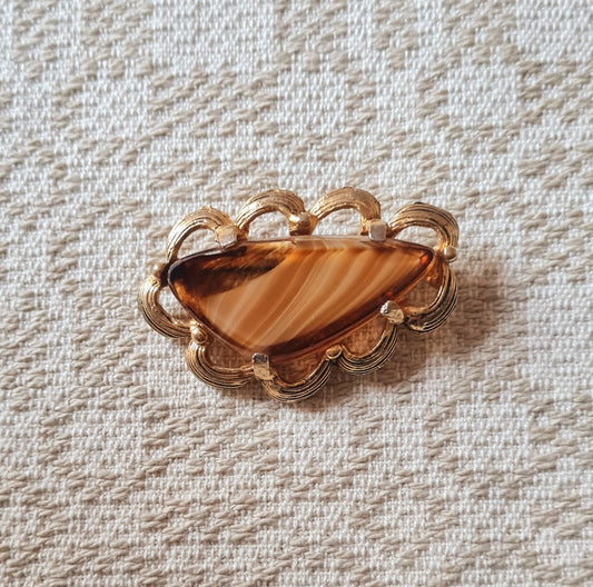 Spilla con pietra color ambra, montatura dorata e dettagli ornamentali