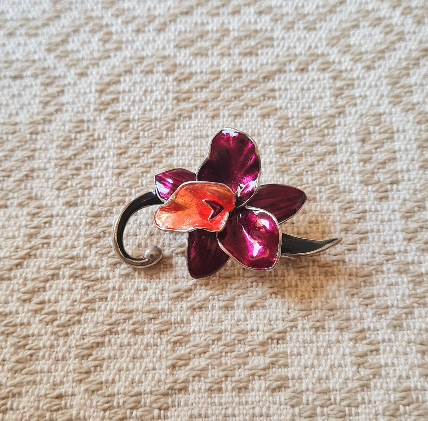 Spilla a forma di fiore con petali bordeaux, montatura argento.